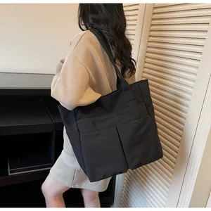 Vista dettagliata di una borsa tote nera capiente con tasche multiple e manici.