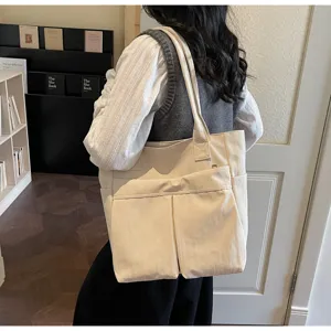 Vista dettagliata di una elegante borsa tote in tela beige con tasche anteriori per uso.