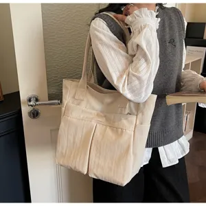 Dettaglio borsa shopper in tela con tasche frontali multiple e grande capienza.