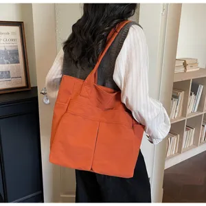 Vista dettagliata della grande borsa tote arancione in tela, borsa a spalla casual con tasche.