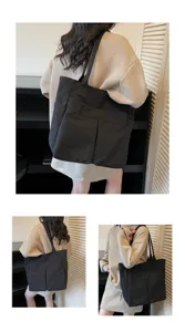 Vista dettagliata di una semplice borsa tote nera con tasche frontali e grande capacità.