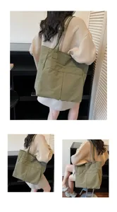 Borsa shopper in tela verde vista di dettaglio con tasche frontali e comoda tracolla regolabile.