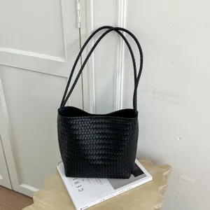 Detail shot of black woven leather shoulder bag showing intricate texture and twin straps.