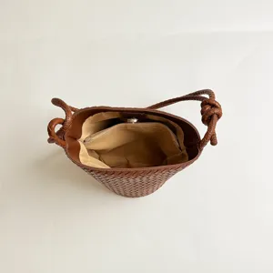 Detailed view of the brown woven bucket bag showing interior lining and knotted strap.