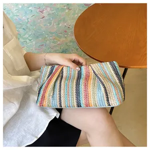Detailed view of the colorful woven clutch bag showing fine straw texture and vibrant striped design.