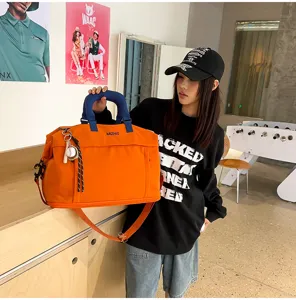 Grande borsa da viaggio arancione con manici blu, perfetta per brevi viaggi del fine settimana.