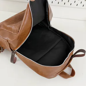 Detailed view of brown leather backpack interior zipper pocket and crocodile embossed front.