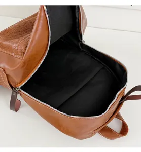 Detail view of brown leather retro backpack with crocodile pattern pocket and spacious inside.
