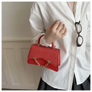 Detail view of a chic red woven chain handbag, featuring stylish shoulder strap and gold hardware.