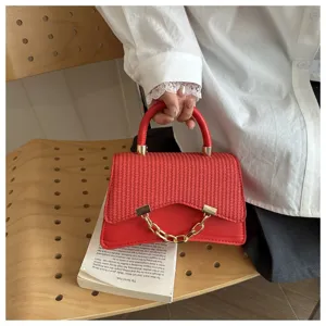 Red straw woven handbag with metal chain and top handle, stylish daily summer accessory.