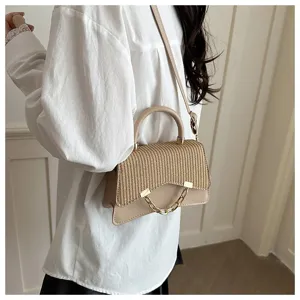 Close-up shot of a stylish straw-woven women handbag with metal chain detail worn by model.