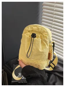 Detail shot of a trendy yellow canvas crossbody phone bag with drawstring and adjustable strap.