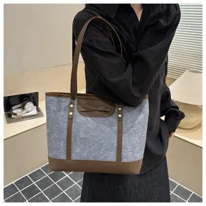 Detail view of stylish women's commuter tote bag featuring brown trim and bow accent.