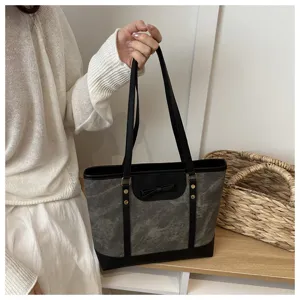 Detail shot of the stylish grey tote bag featuring black handles, bow and contrasting trim.