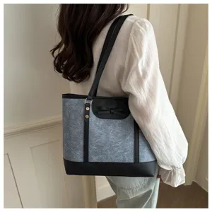 Stylish women's grey shoulder tote bag detail view with black bow and leather trim design.