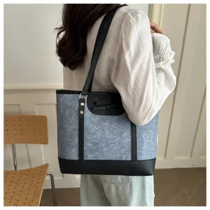 Casual commuter tote bag detail showing shoulder strap, bow decoration, and contrast leather trim.