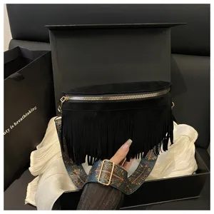 Detailed view of the black fringe crossbody bag, showing texture and patterned wide strap.