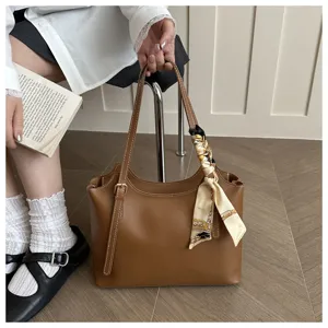 Dettaglio borsa shopper in pelle PU marrone con elegante foulard in seta stampato.