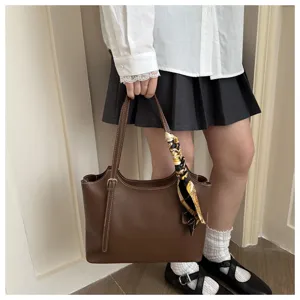 Dettaglio della borsa a spalla marrone con foulard elegante, che mostra la grande capienza.