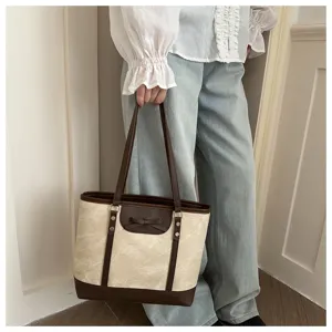 Stylish canvas tote bag featuring contrast leather trim and cute bow detail for women daily commute.