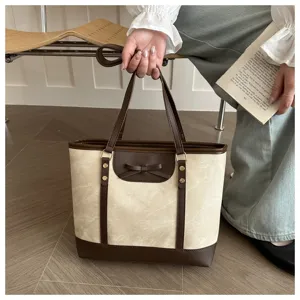 Detail view of stylish beige and brown tote bag with cute bow and handles for daily commuting.