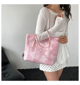 Vue détaillée du sac cabas texturé rose abstrait, montrant les doubles anses et le badge logo.