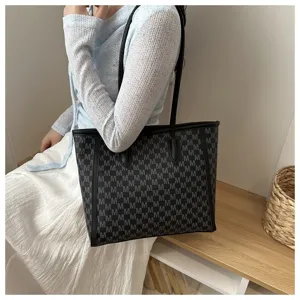 Detail view of large capacity black M monogram tote bag, shoulder commuter style with handles.