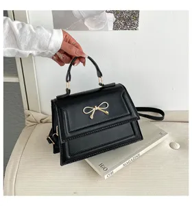 Vue rapprochée et détaillée d'un élégant sac à main noir chic avec un beau nœud doré.