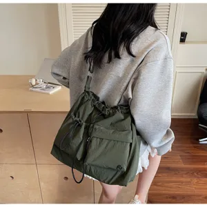 Detail shot of a dark green nylon drawstring shoulder bag with multiple exterior pockets.