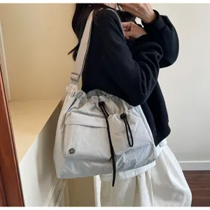 Lightweight casual drawstring shoulder bag detail, off-white nylon tote with front pockets.