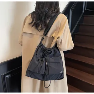 Detail view of the stylish black nylon drawstring shoulder bag featuring front pockets.