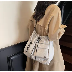 Detail view of stylish minimalist drawstring shoulder bag, lightweight casual crossbody tote.