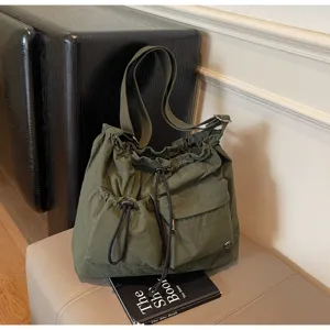 Detail view of the green slouchy drawstring shoulder bag, featuring multiple pockets.