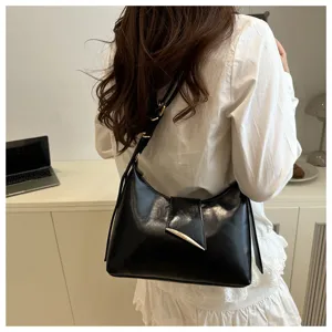 Detail view of black leather underarm shoulder bag with metal buckle and strap.