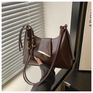 Close-up of dark brown glossy leather underarm shoulder bag featuring metal buckles and straps.