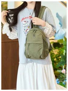 Green nylon backpack detail showcasing multi-pocket design, zippers and casual style.