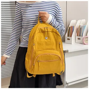Close-up detail of a bright yellow casual backpack worn by a model indoors, showing zippers.