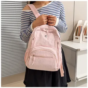 Detailed lifestyle view of a casual pink nylon backpack with multi-pocket design and smooth zippers.