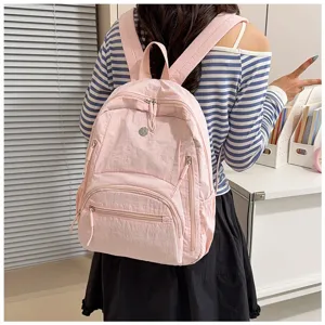 Detail view showing the multi-pocket design and nylon texture of the pink casual backpack.
