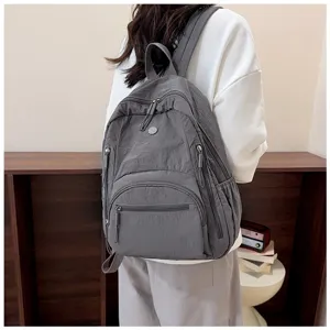 Detail view of the minimalist dark grey backpack featuring multiple functional zipper pockets.