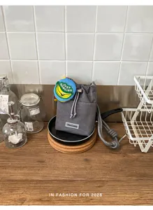 Grijze mesh schoudertas voor waterfles met schattige bananenhangers, casual zomertasje.