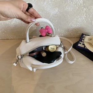 Bolso de mano blanco de cuero de moda con lindo colgante de lazo para mujer elegante.