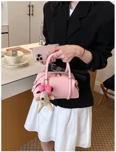 Elegante bolso de mano de cuero rosa para mujer con dije de peluche y cierre de doble cremallera.