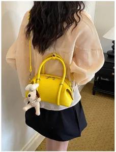 Vista detallada del elegante bolso de cuero amarillo con colgante de perro y correa.
