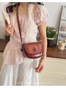 Vintage dark red saddle bag detail view showing elegant crossbody wear and premium texture.