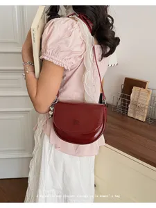 Vintage red saddle bag for women, elegant shoulder bag with chic heart charm and strap.