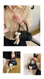Vista detallada del elegante bolso tipo almohada de cuero negro con dije de peluche para mujer.