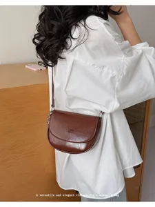 Vintage glossy brown saddle bag for women, elegant crossbody purse with chic chain detail.