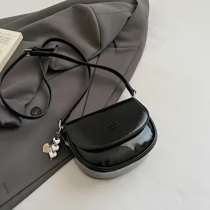 Detail view of the black patent leather saddle crossbody bag, stylish mini shoulder bag.