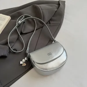 Stylish silver saddle crossbody bag for women, trendy mini shoulder bag with metal heart charms.